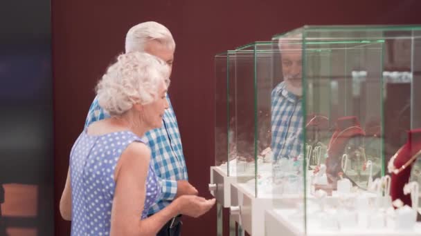 Šťastný starý pár stojící poblíž vitríny s šperky — Stock video