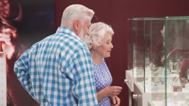 Volwassen dame met echtgenoot staan in de buurt showcase met sieraden — Stockvideo