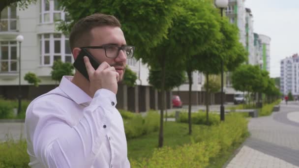 Brodaty człowiek mówi na smartfonie na zewnątrz. — Wideo stockowe