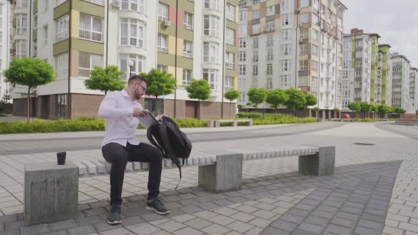 Молодий фрілансер вставляє ноутбук у рюкзак . — стокове відео