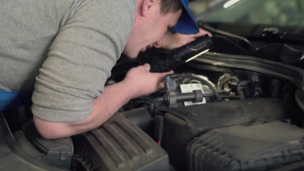 Mecânico de carro com lanterna que inspeciona o capot do carro . — Vídeo de Stock