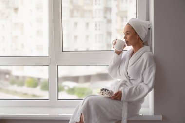 Pencere kenarında bir fincan kahve içen kız..