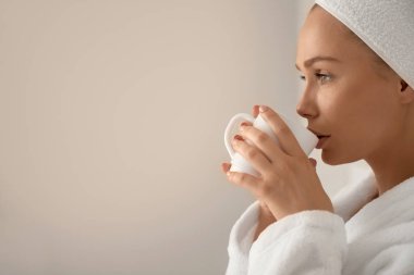 Bornozlu kız yatakta kahve içiyor..