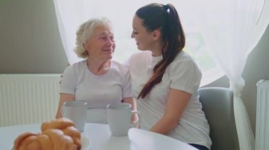 Woman hugging and kissing grandmother.
