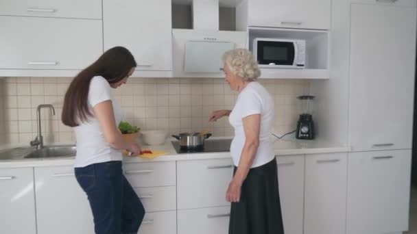 Uśmiechnięta kobieta pomaga babci gotować. — Wideo stockowe
