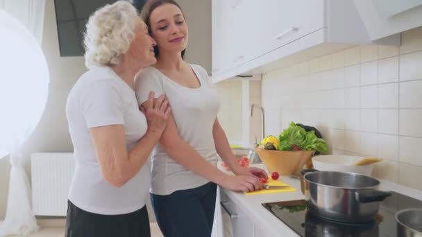 Vieja mujer abrazando nieta en cocina . — Vídeo de stock