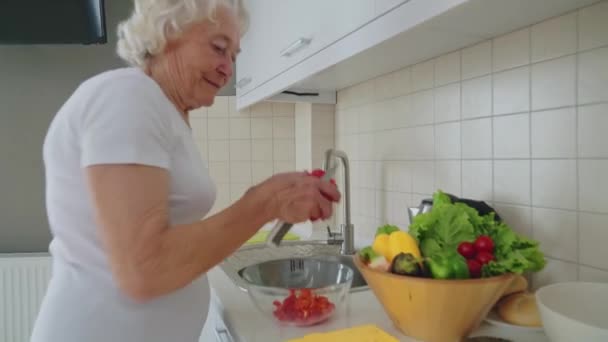 Senior kvinna gör sallad i köket. — Stockvideo