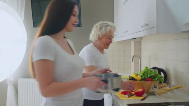 Genç bir kadın büyükannenin yemek yapmasına yardım ediyor.. — Stok video