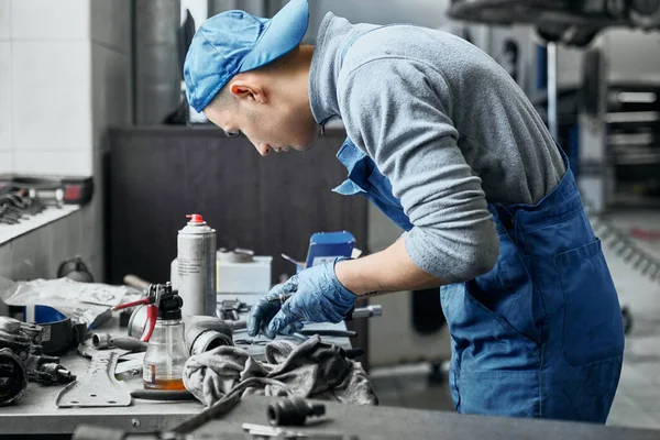 Young repairman doing restoration of old details for car — ストック写真