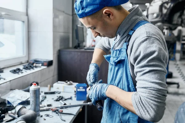 Opravář v autoservisu pracuje s malými detaily na stole — Stock fotografie