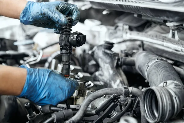 Male specialist replacing ignition coil and old nozzles — ストック写真