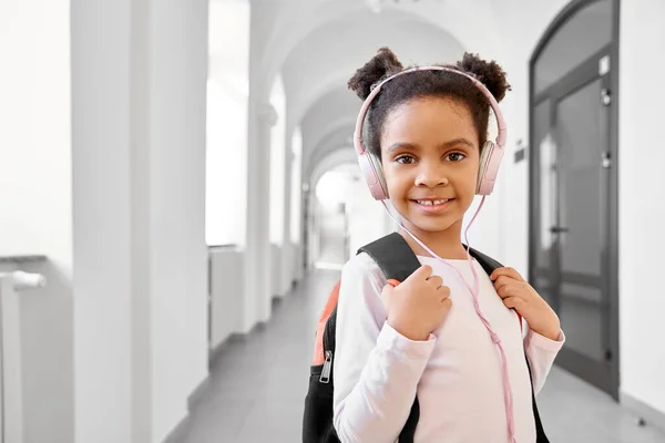 African school girl wearing headphones standing at corridor. — ストック写真