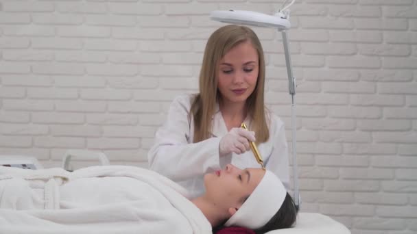Красивая молодая девушка делает массаж лица в спа-салоне — стоковое видео