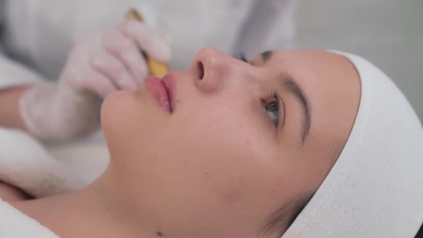 Chica joven recibiendo masaje facial en el salón de belleza moderno — Vídeos de Stock