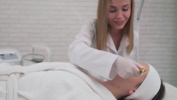 Esteticista femenina haciendo masaje facial estimulante para chica — Vídeos de Stock