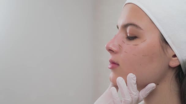 Vista lateral de la chica con líneas de perforación en la cara en la clínica — Vídeo de stock