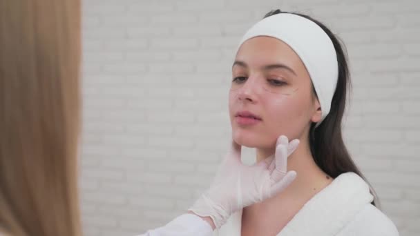 Женщина-косметолог готовит лицо клиента к косметической операции — стоковое видео