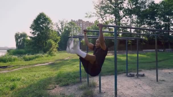 Gespierde atleet doet zijn buikspieroefeningen in het groene park — Stockvideo