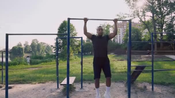 Gimnasio al aire libre con hombre africano haciendo tire hacia arriba en la barra horizontal — Vídeos de Stock