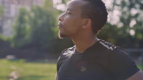 Щасливий молодий афроамериканець, який дихає свіжим повітрям у парку. — стокове відео