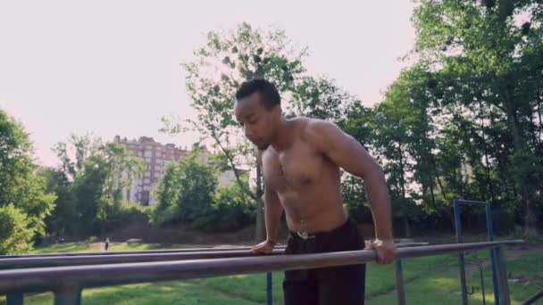 Fit man with naked torso doing triceps dips on parallel bars — 비디오