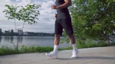Muscular african man running along the city lake
