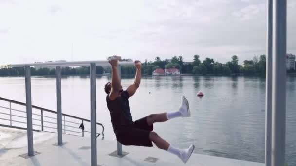 Muscular man doing abdominal exercises near the lake — Stock Video