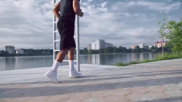 Muscular young afro american guy running near lake — Stockvideo