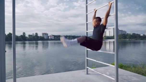 Silný afro muž dělá břicha tím, že zvedne nohy do horizontální — Stock video