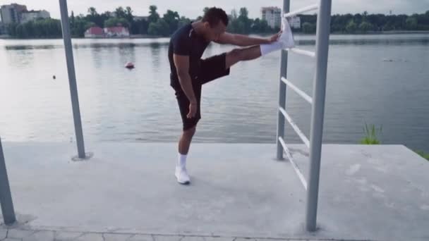 Retrato de comprimento total do cara africano esticando a perna perto do lago — Vídeo de Stock
