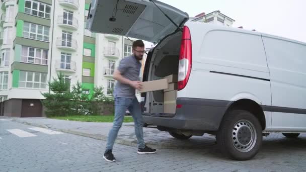 Hezký doručovatel vytahuje balíčky z kufru auta — Stock video