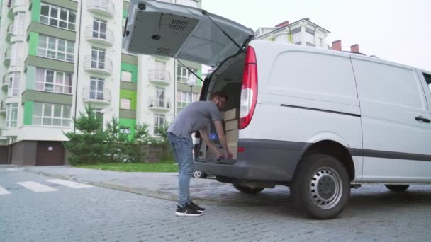 Бородатий кур'єр розвантажує картонні коробки з багажника автомобіля — стокове відео