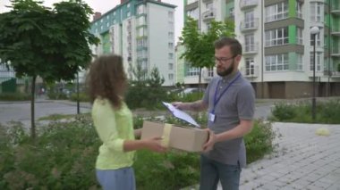 Happy female client receiving parcel from male courier