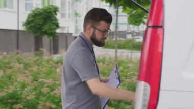 Kurye, teslimat için araba bagajından karton kutu alıyor.