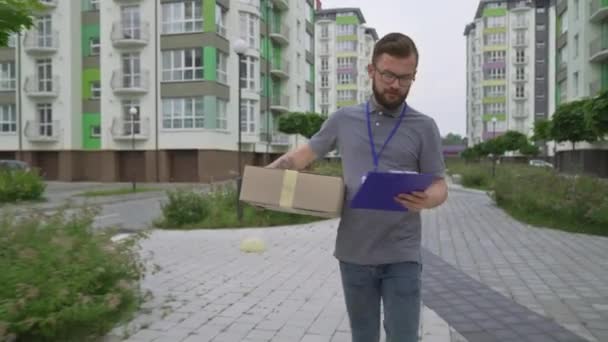 Jonge man met baard op zoek naar klantenadres om doos te leveren — Stockvideo