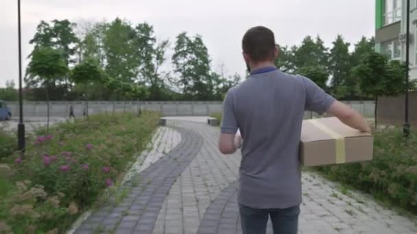 Unga skäggiga kurir levererar paket till kundens hus — Stockvideo