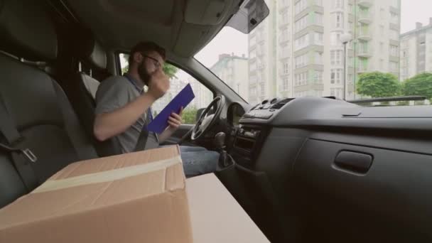 Leverans man sitter i bilen och anteckningar i Urklipp — Stockvideo