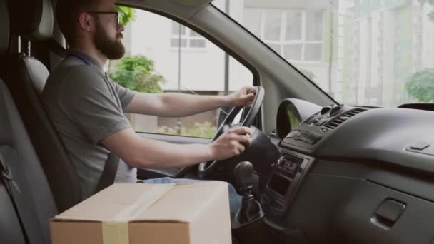 Seitenansicht eines jungen Kuriers, der Auto mit Papierschachteln fährt — Stockvideo