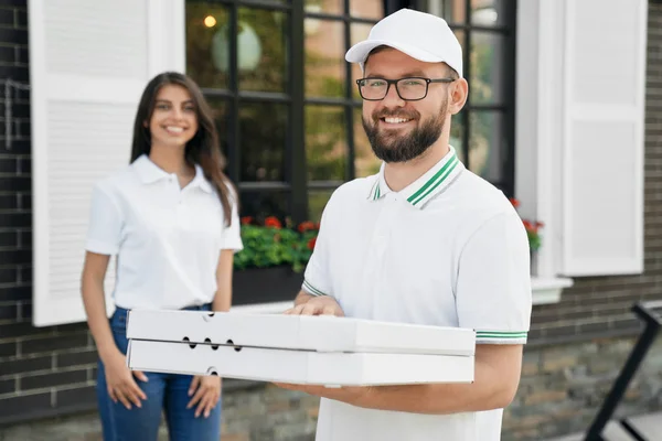 Glimlachende bezorger met dozen pizza. — Stockfoto