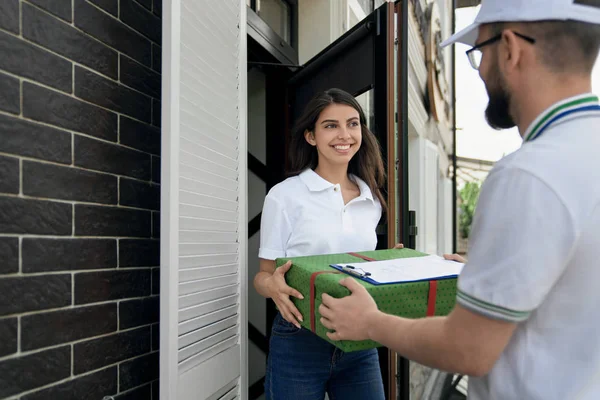 Bezorger geeft geschenkdoos en map aan vrouw. — Stockfoto