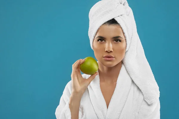 Portret van een vrouw in badjas met appel. — Stockfoto