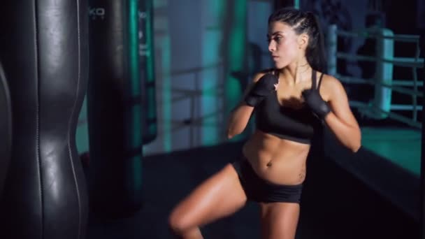 Žena ve sportovních obvazech bít boxerský pytel. — Stock video