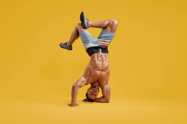 Genç kaslı vücut geliştirici amuda kalkıyor.