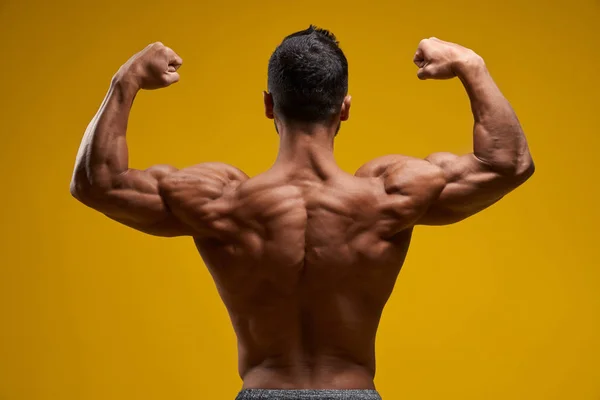 Skjortlös man som demonstrerar muskulösa armar och axlar — Stockfoto