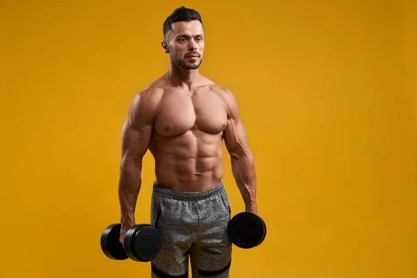 Strong athletic man holding dumbbells — Stock Photo, Image
