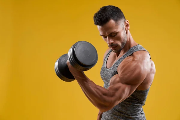 Muscular young man pumping up biceps — Stock Photo, Image