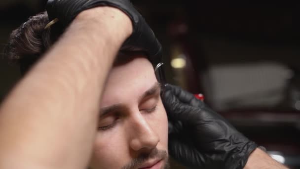 Homem barbudo recebendo correção de sobrancelhas na barbearia — Vídeo de Stock