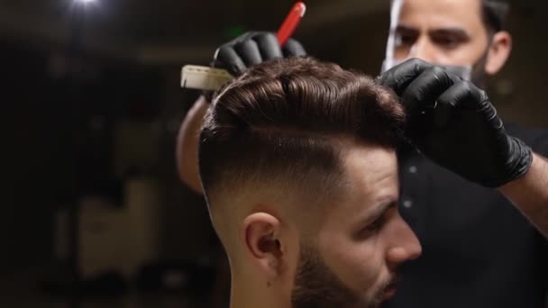 Zelfverzekerde mannelijke kapper doet trendy kapsel voor klant — Stockvideo