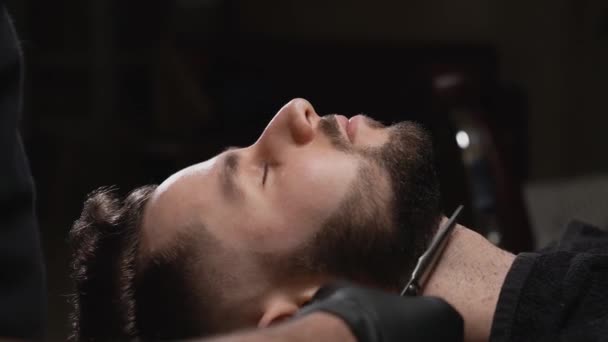 Vista lateral do cliente masculino durante a preparação da barba na barbearia — Vídeo de Stock