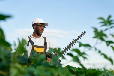 Çalı biçme makinesiyle çalı biçen Afrikalı adamın portresi